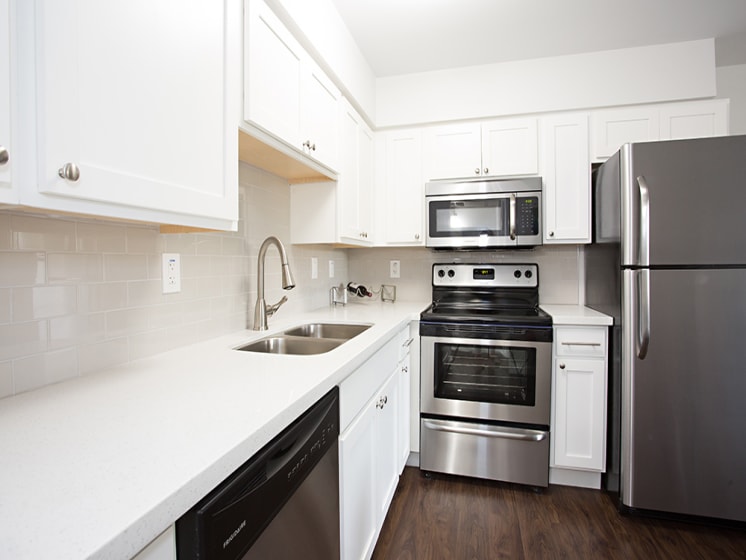 Phoenix apartment kitchen with quartz countertops, hardwood floors, and stainless steel appliances at Arcadia Gardens